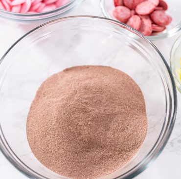 Measured ingredients in a glass mixing bowl to prepare hot chocolate bombs.