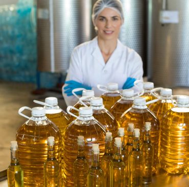 Portrait of confident female worker standing with arms crossed in oil factory
