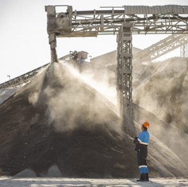 Quarry worker standing beside pile of aggregate in quarry