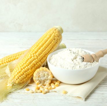 Raw corn and flour on white wooden table