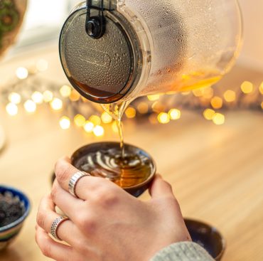 Tea ceremony. Professional tea brewing. Tea. Meditation with tea. High quality photo. Woman pouring tea from a glass teapot into a tea bowl. Hands with tea close-up.